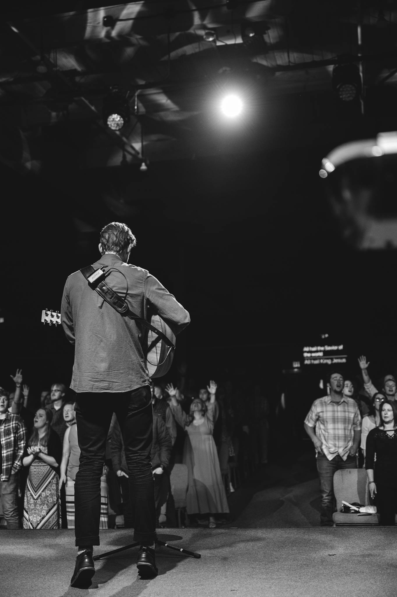 Captivating black and white shot of a guitarist performing on stage with an enthusiastic audience.