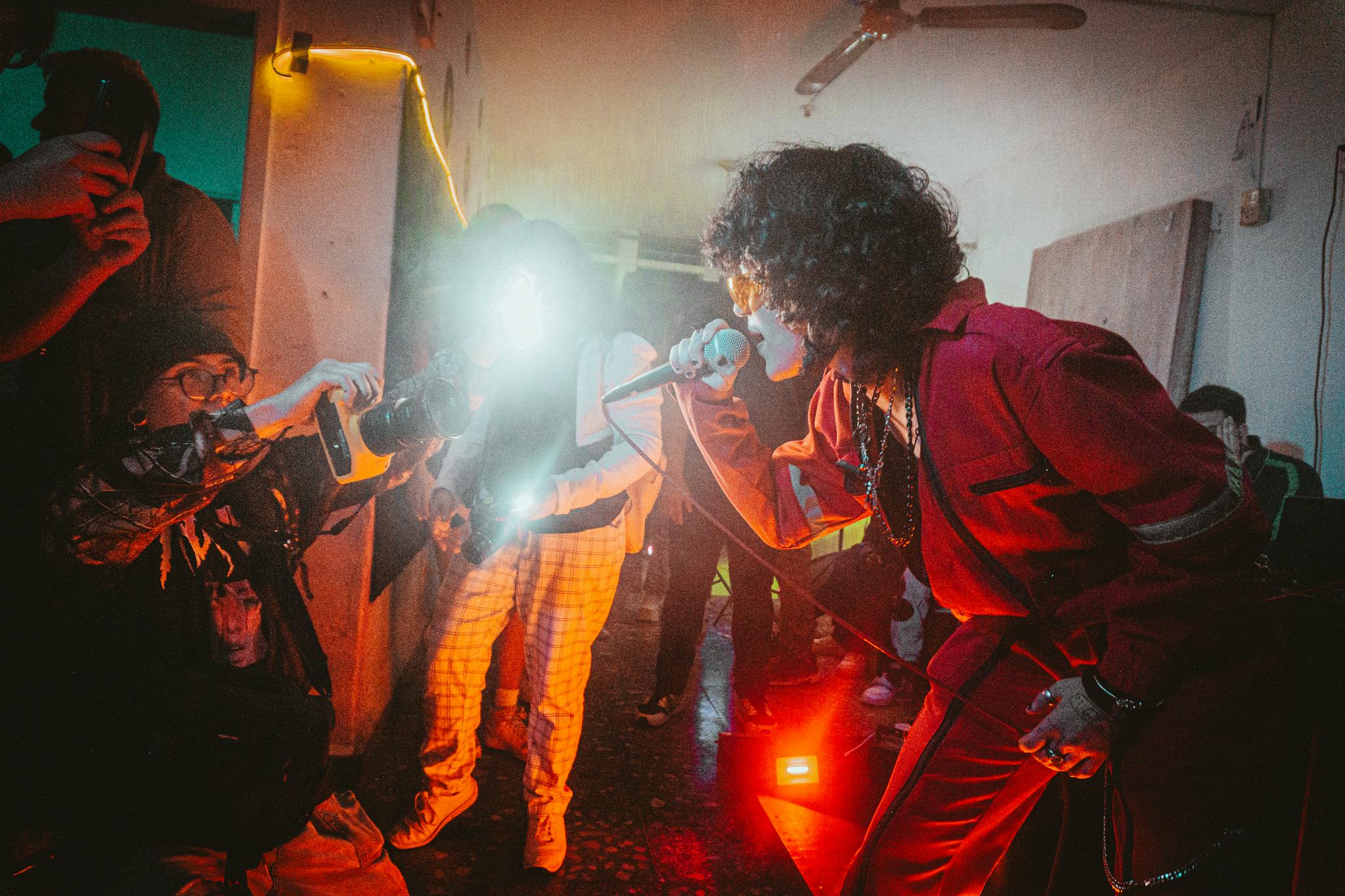 Dynamic photo of a singer performing live on stage with photographers capturing the moment.