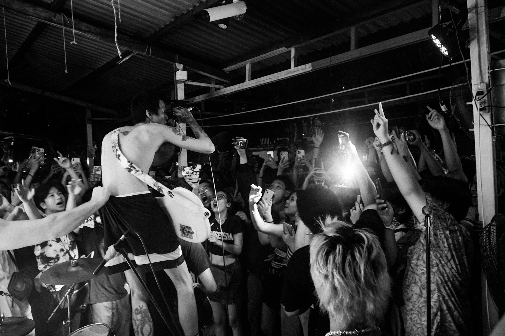 Energetic live music concert with crowd engagement and artist performance in black and white.